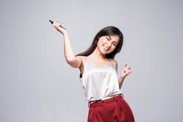 Winning success asian woman happy ecstatic celebrating being a winner isolated on white wall waist up.