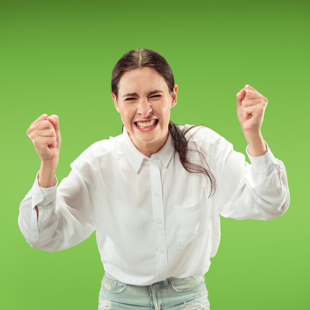 Бесплатное фото Победа успеха счастливая женщина празднует быть победителем. динамическое изображение кавказской женской модели на зеленой стене студии. концепция победы, восторг. концепция человеческих лицевых эмоций. модные цвета