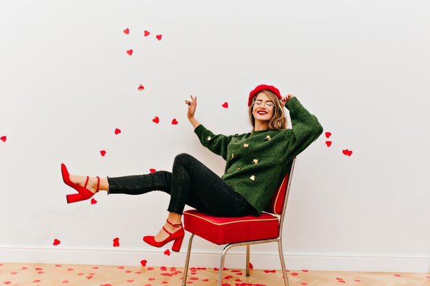 Winsome lady in glasses having fun in studio decorated with hearts