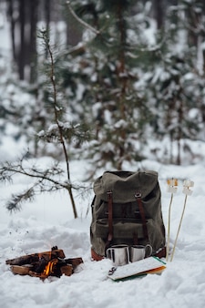 겨울 캠핑. 여행 배낭,지도, 두 찻잔 및 눈에 마시 멜로와 모닥불