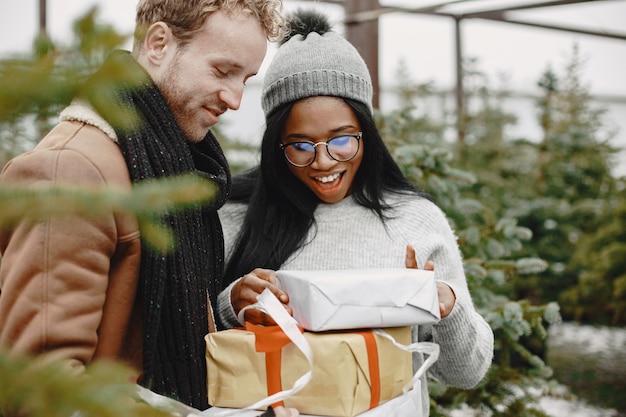 Free photo winter concept. guy in a brown coat. salesman of christmas tree. international couple.