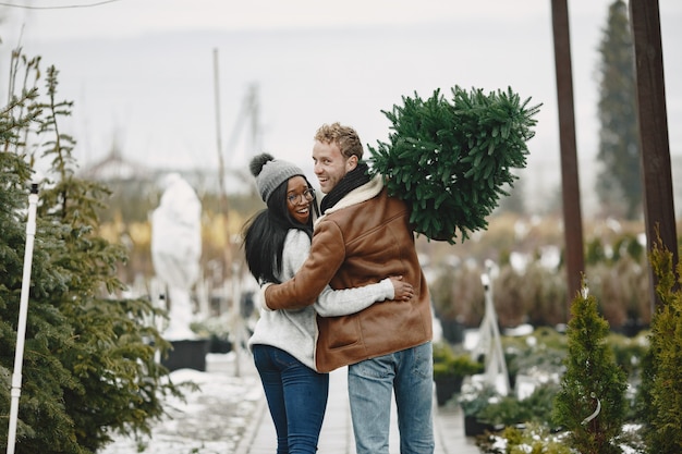 Concetto di inverno. ragazzo con un cappotto marrone. venditore di albero di natale. coppia internazionale.