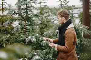 Free photo winter concept. guy in a brown coat. salesman of christmas tree.