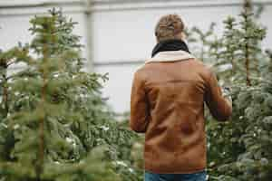 Free photo winter concept. guy in a brown coat. salesman of christmas tree.