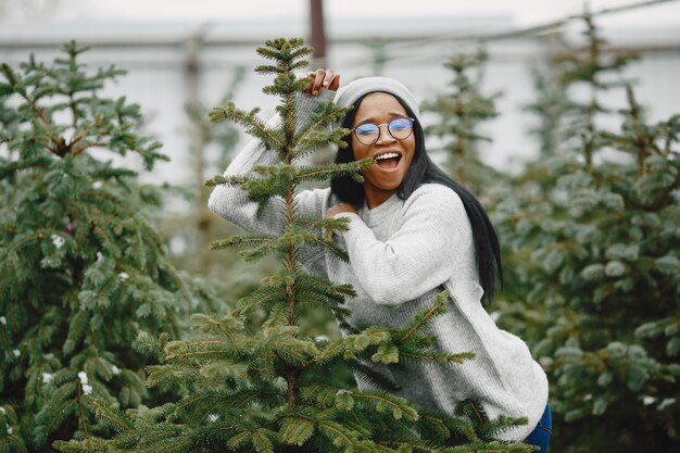 Winter concept. Woman in a gray sweater. Saleswoman of Christmas Tree.