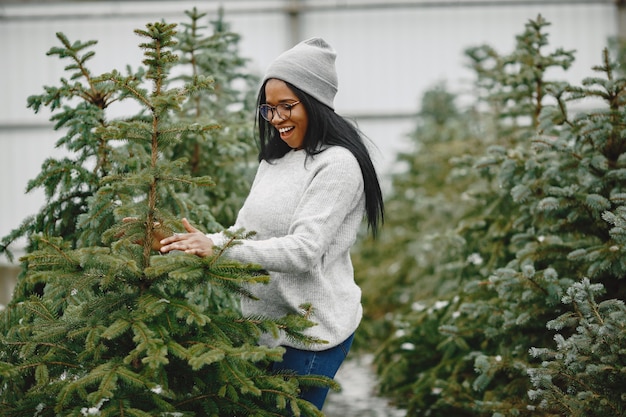 Foto gratuita concetto di inverno. donna in un maglione grigio. commessa di albero di natale.