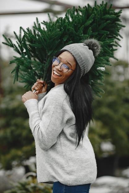 Concetto di inverno. donna in un maglione grigio. commessa di albero di natale.