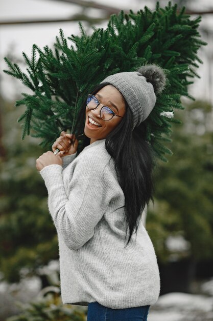 Winter concept. Woman in a gray sweater. Saleswoman of Christmas Tree.