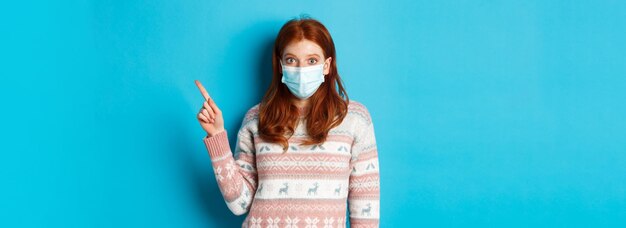 Winter covid and quarantine concept intrigued redhead girl in medical mask picking product looking a