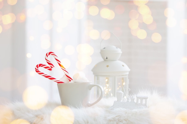 흰색 나무 배경에 사탕 지팡이와 뜨거운 음료의 겨울 컵