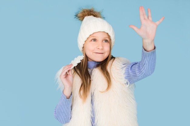 Зимняя одетая маленькая девочка поднимает руку