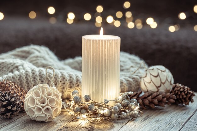 Winter festive background with burning candle and home decor details on blurred background with bokeh.