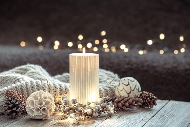 Winter festive background with burning candle and home decor details on blurred background with bokeh.