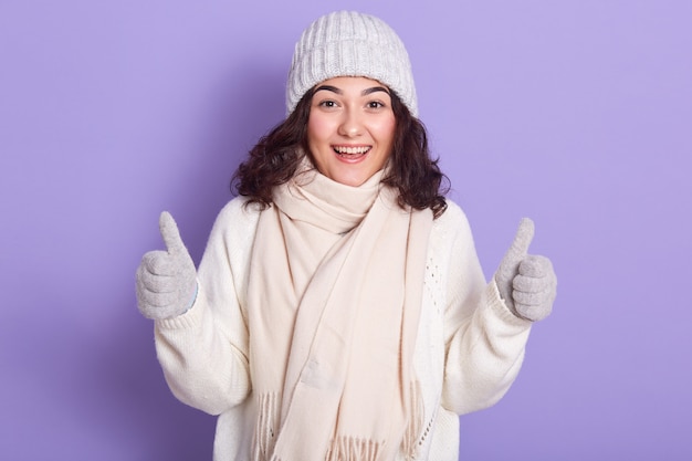 Зимняя девушка с темными волнистыми волосами одевает белый теплый свитер