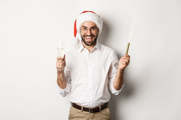 Зимние праздники и торжества. Красивый бородатый мужчина в новогодней вечеринке с блеском фейерверка и шампанским в шляпе санта-клауса