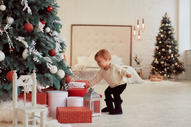 Winter holidays decorations. Warm colors. Beautiful little girl plays with present boxes