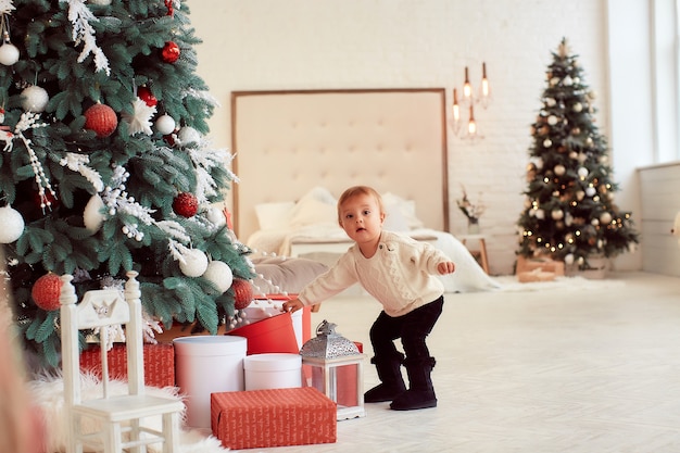 Winter holidays decorations. Warm colors. Beautiful little girl plays with present boxes 