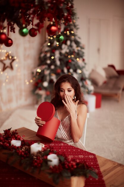Winter holidays decorations. Warm colors. Charming brunette woman in beige dress 