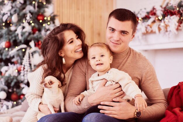 Winter holidays decorations. Warm colors. Family portrait. Mom, dad and their little daughter 