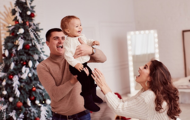 Winter holidays decorations. Warm colors. Family portrait. Mom, dad and their little daughter