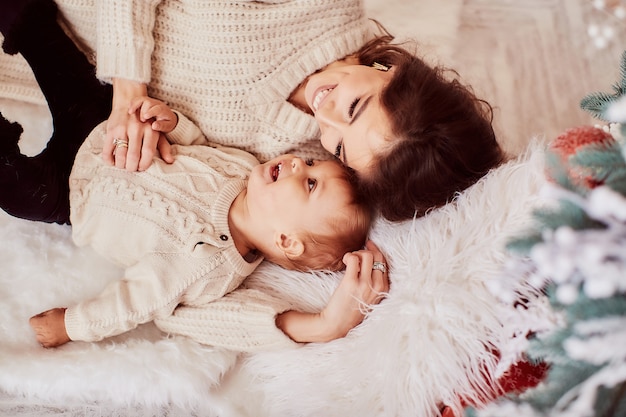 Winter holidays decorations. Warm colors. Family portrait. Mom and little lovely daughter 