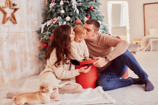 Winter holidays decorations. Warm colors. Mom, dad and little daughter play with a dog 