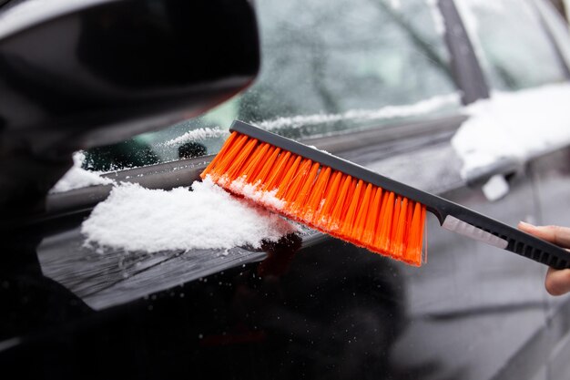 자동차의 겨울 문제 남자는 브러시로 눈에서 차를 청소합니다