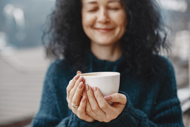 山での冬休み。女性の巻き毛。コーヒーと白いカップ。