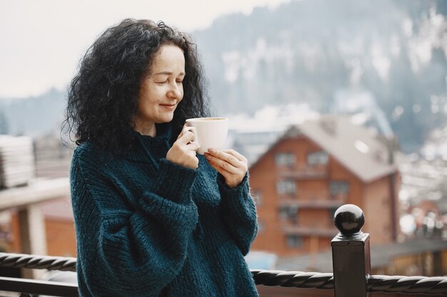 산에서 겨울 방학. 여성의 곱슬 머리. 커피와 함께 흰색 컵입니다.
