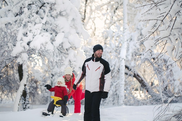 눈오는 날 아버지가 어린 아들과 함께 썰매를 끄는 겨울 산책