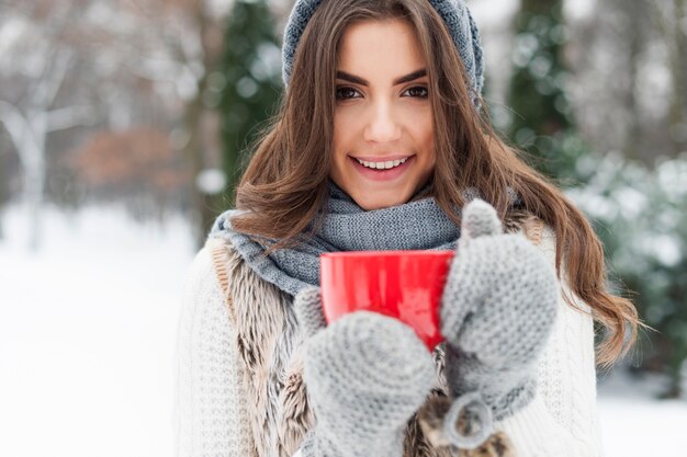 熱いお茶のカップを持つ冬の女性