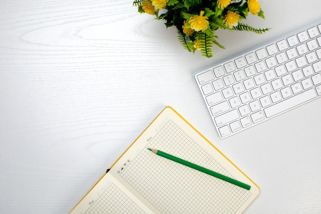 Wireless keyboard and opened notepad with pencil