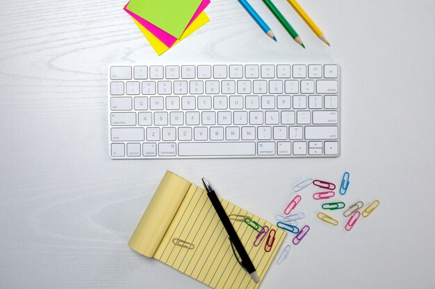 Wireless keyboard and yellow notepad on the table