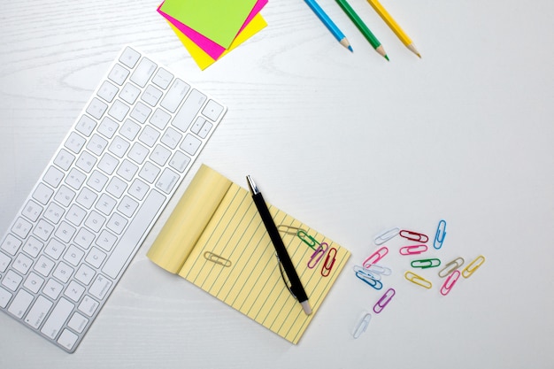 Wireless keyboard and yellow notepad on the table