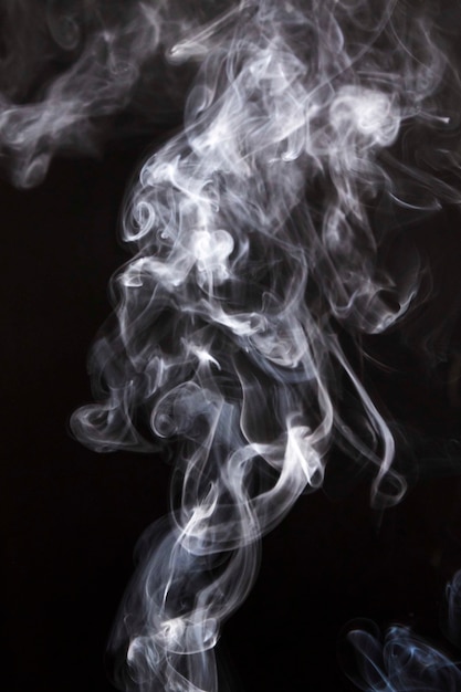 Free photo wispy smoke clouds spread on black background