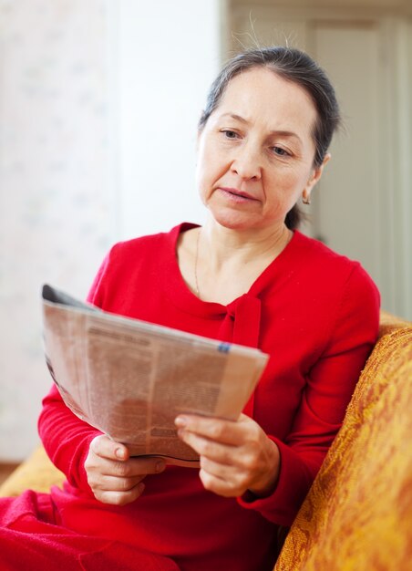 wistful woman reading newspaper