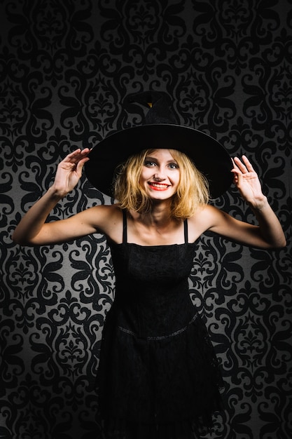 Free photo witch girl holding hat and smiling