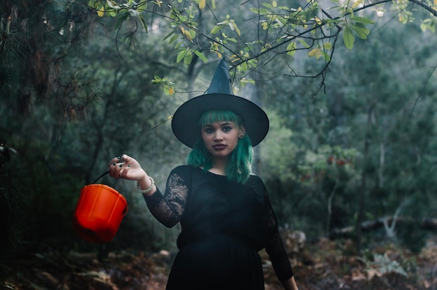 Witch girl with bucket in wood