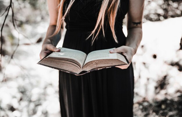 Witch with aged book in sunny forest