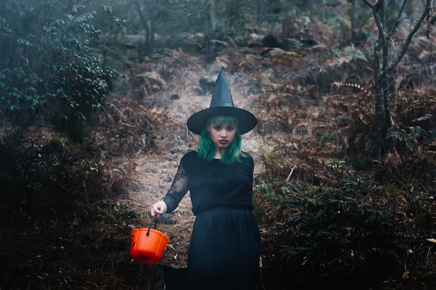 Free photo witch with bucket in forest