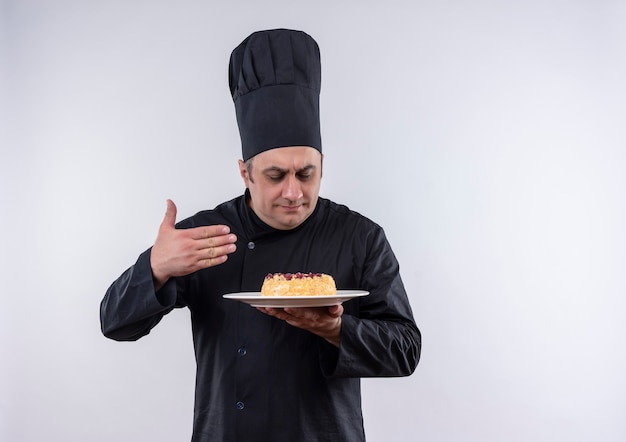 그의 손에 접시에 케이크를 스니핑 요리사 유니폼에 눈을 감고 중년 남성 요리사