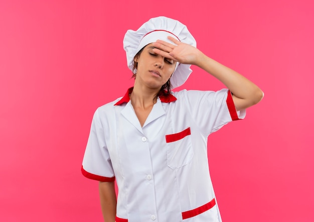 With closed eyes tired young female cook wearing chef uniform putting hand on forehead with copy space