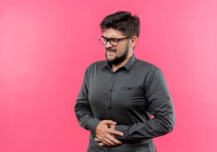 मुफ़्त फोटो with closed eyes unpleased young businessman wearing glasses grabbed aching stomach isolated on pink background