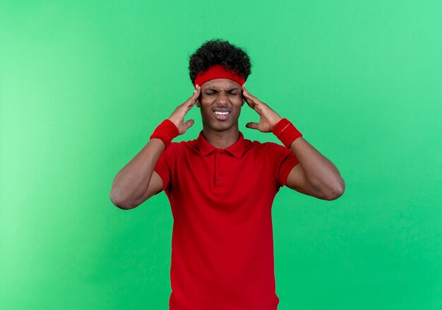 With closed eyes unpleased young sporty man wearing headband