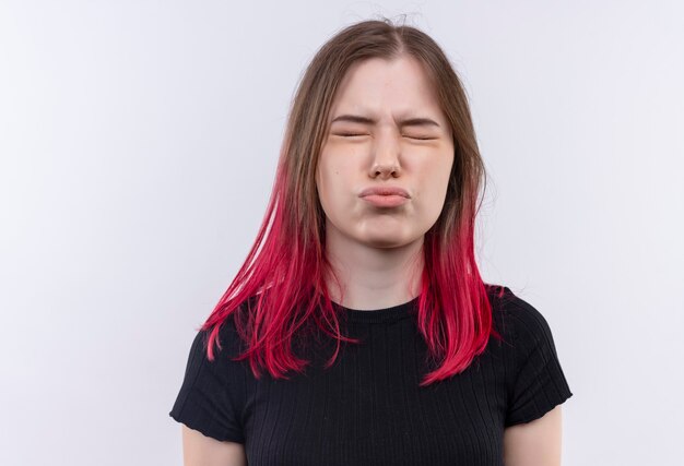 With closed eyes young beautiful girl wearing black t-shirt showing kiss gesture on isolated white wall