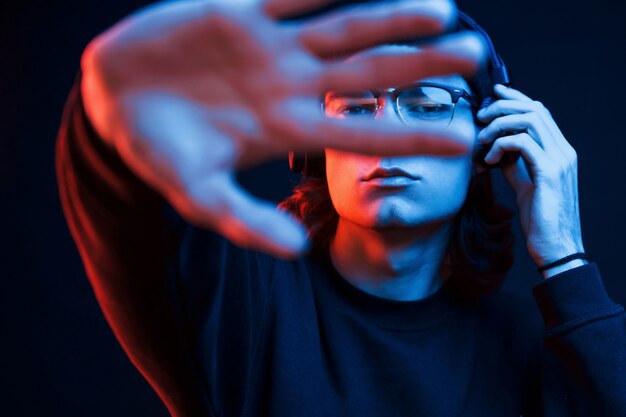 With elongated hand. Studio shot in dark studio with neon light. Portrait of serious man