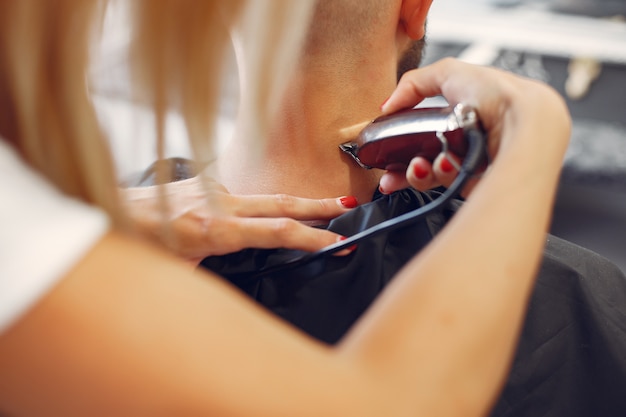 Woma shaving man's beard in a barbershop