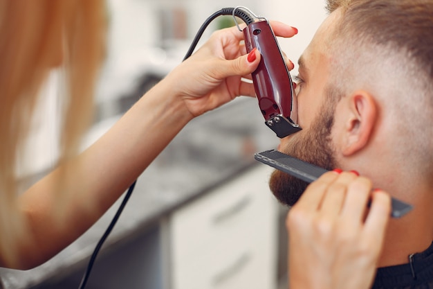 Woma shaving man's beard in a barbershop