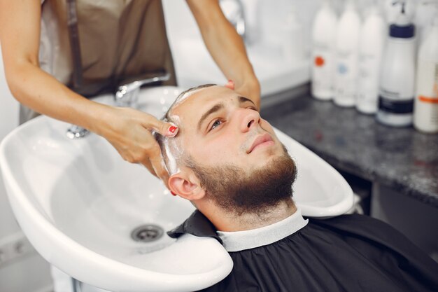 Woma washing man's head in a barbershop