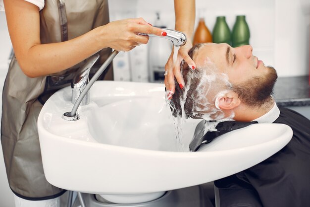 Woma washing man's head in a barbershop